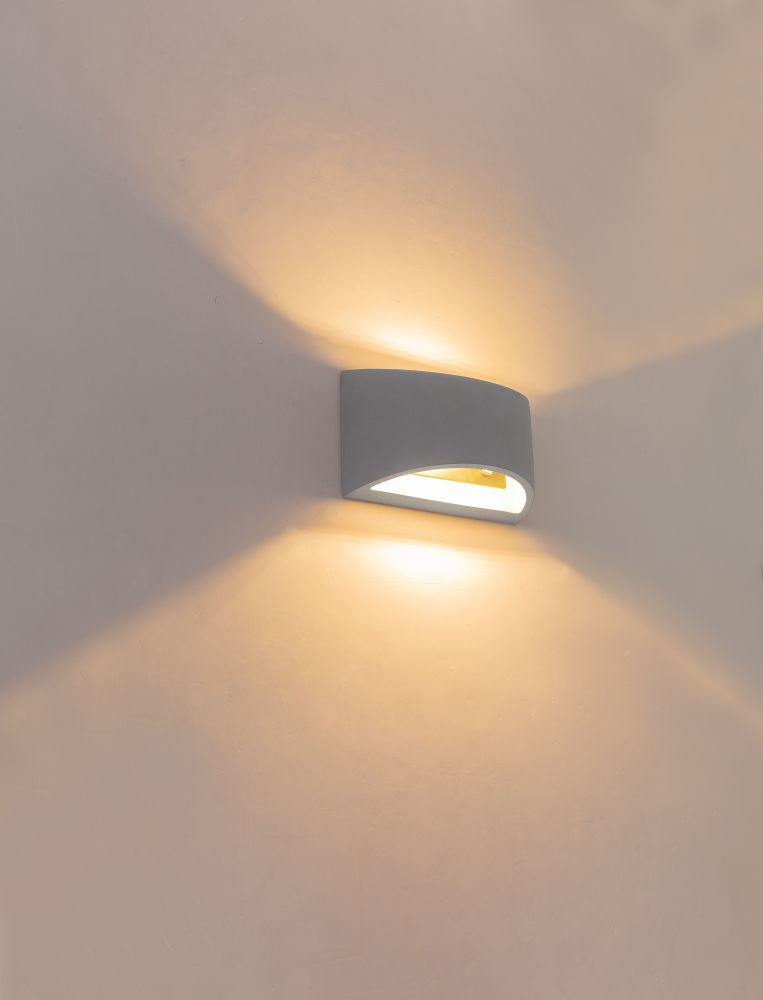 Grauer Wandleuchter wirft warmes Licht nach oben und unten.