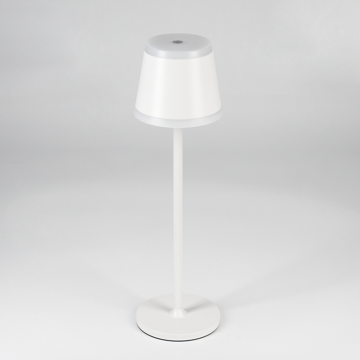 Eine weiße Tischlampe mit rundem Sockel und kegelförmigem Lampenschirm.