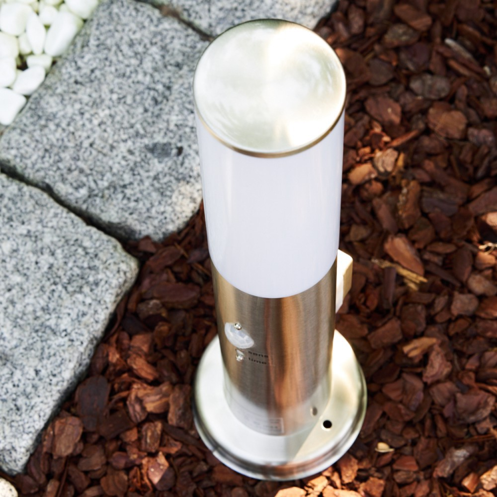 Moderne Edelstahl-Gartenleuchte mit weißem Diffusor auf Rindenmulch und Stein.