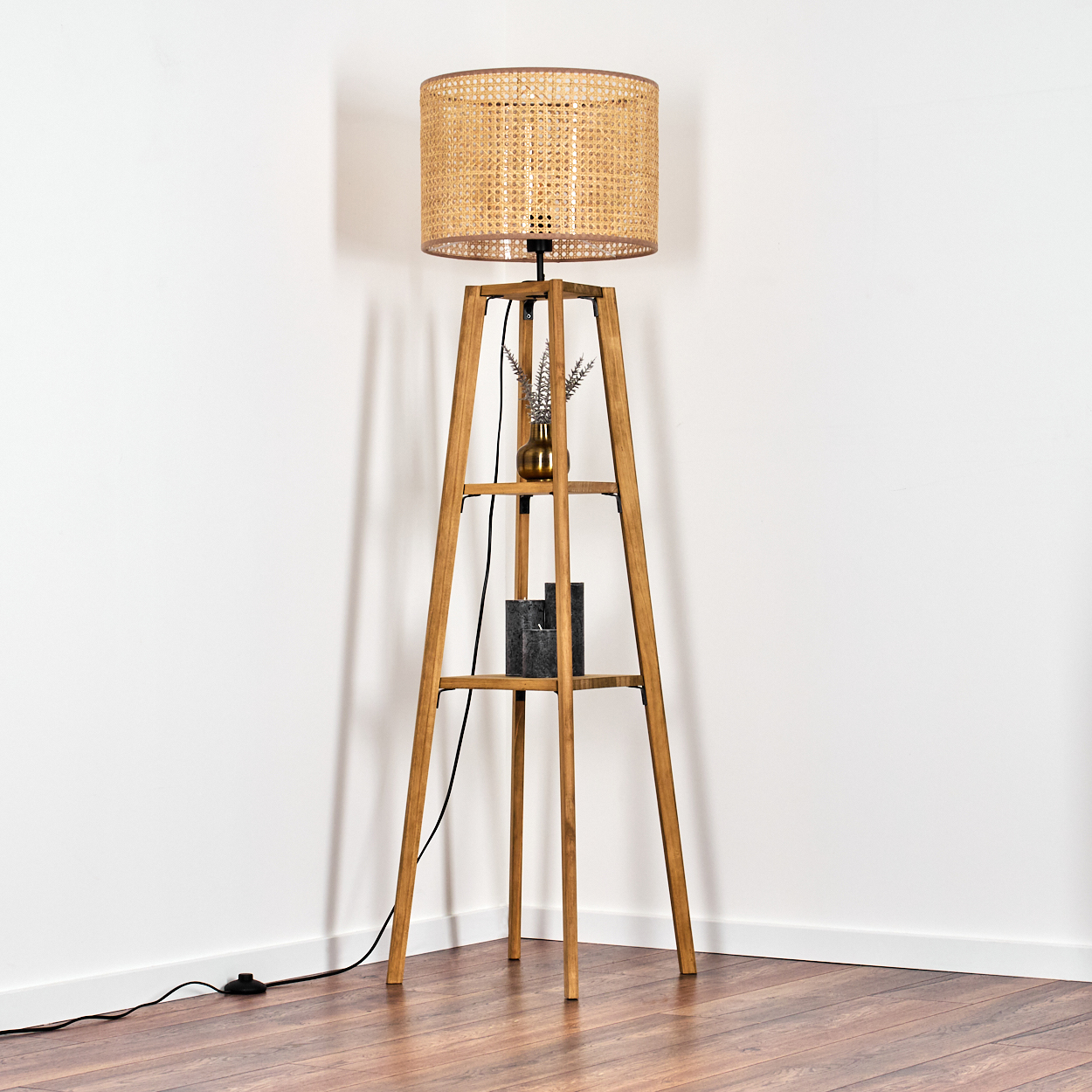 Ein Stehlampe aus Holz mit Rattangehäuse und zwei Ablagen.