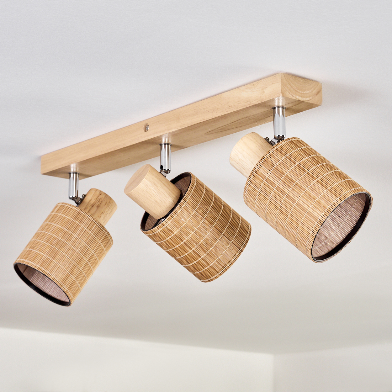 Ein Holzbalken mit drei angebrachten Bambuszylinder-Leuchten.