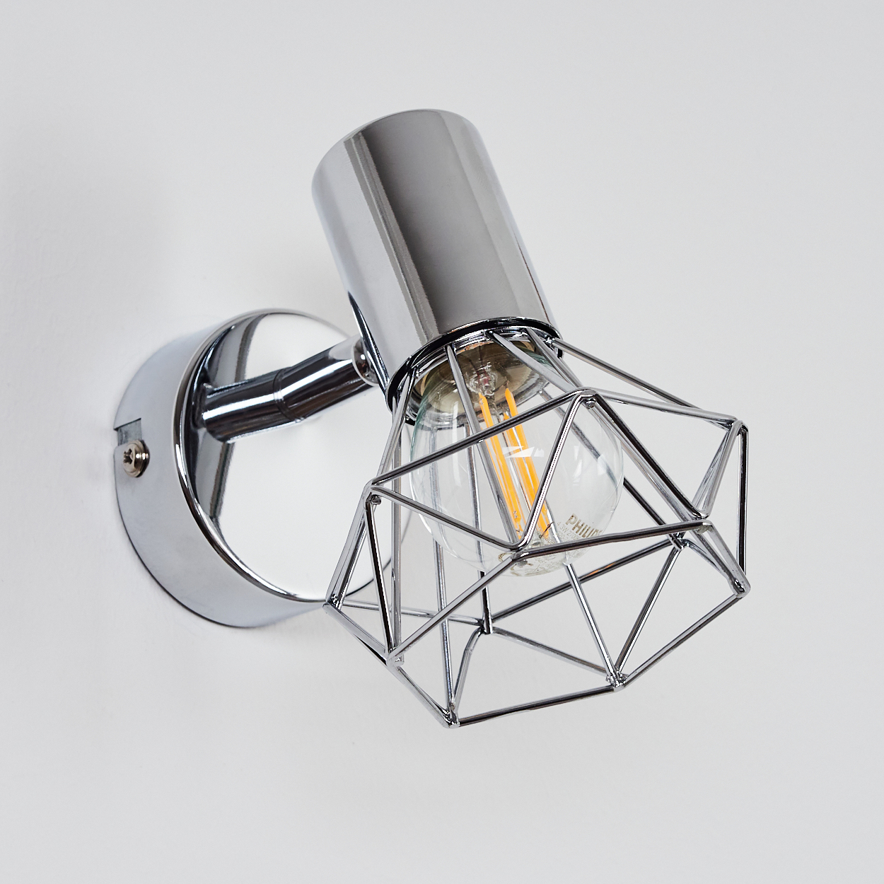 Eine Wandleuchte aus Chrom mit geometrischem Käfig und sichtbarer Edison-Glühbirne.