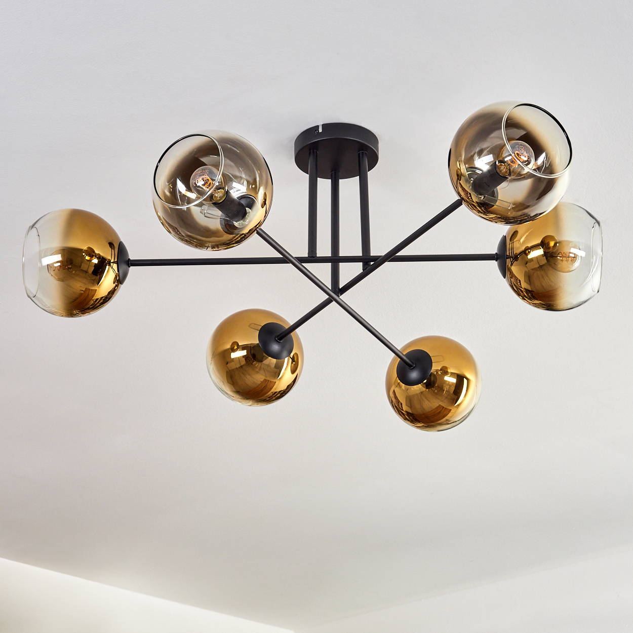 Eine Deckenleuchte mit sechs goldenen Glaskugeln an schwarzen Armen.