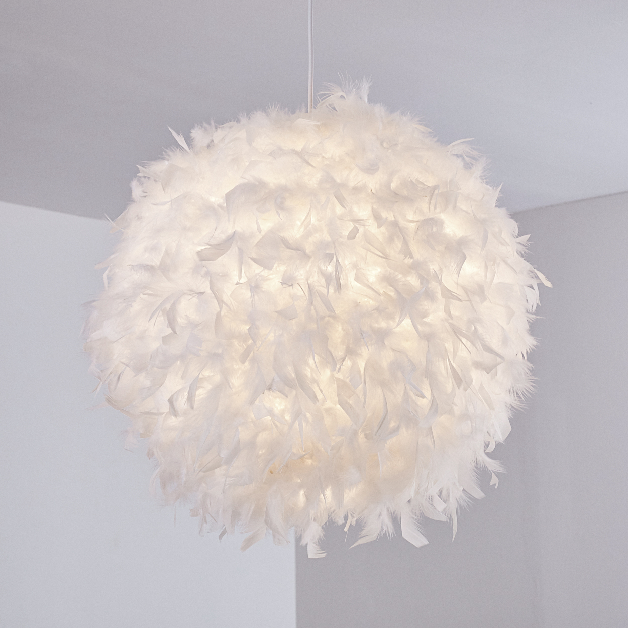 Eine runde weiße Lampe aus Federn hängt von der Decke.