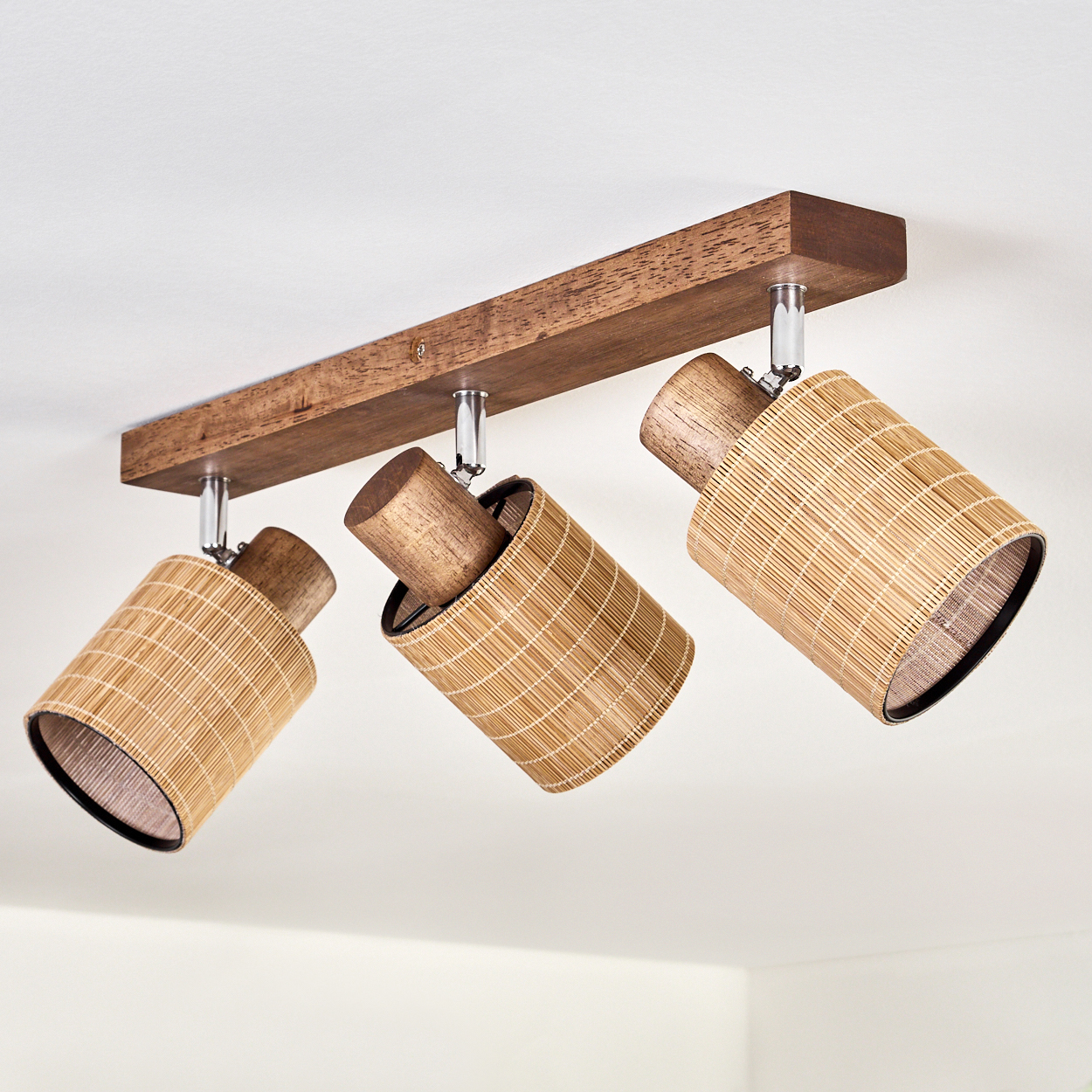 Deckenleuchte mit Holzsockel und drei Körben aus Bambusgeflecht.