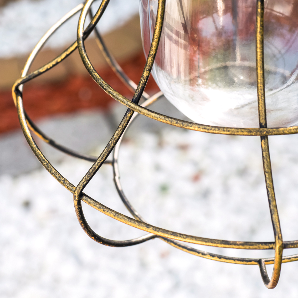 Goldener Drahtkorb schützt Glasbehälter mit weißem Inhalt vor dem Hintergrund von Backstein und Schnee.