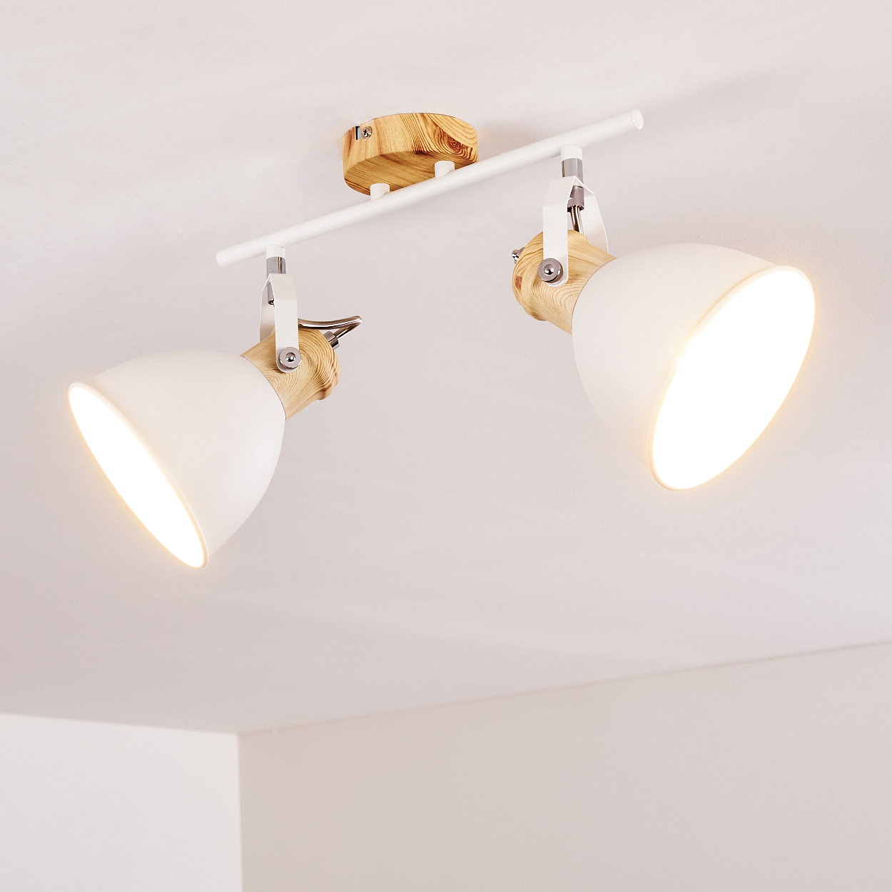 Zwei weiße Deckenstrahler mit Holzdetails an einer weißen Stange montiert.