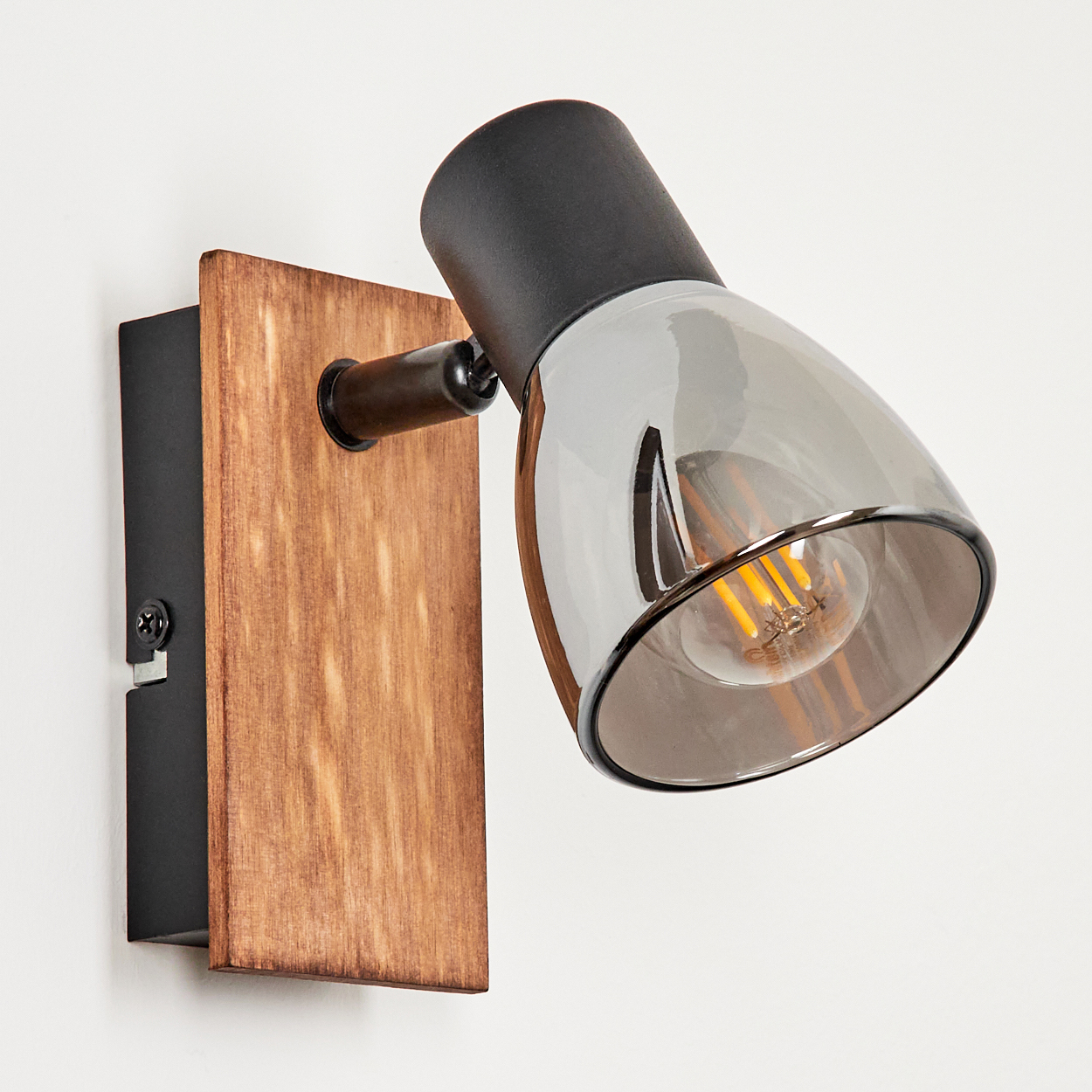 Eine Wandleuchte mit Holzsockel, schwarzem Gehäuse und rauchglasfarbenem Lampenschirm.