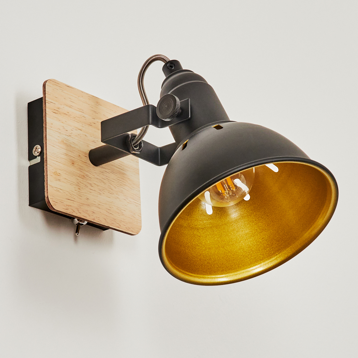 Schwarze Wandleuchte mit Holzsockel und goldenem Schirm. Verstellbar.