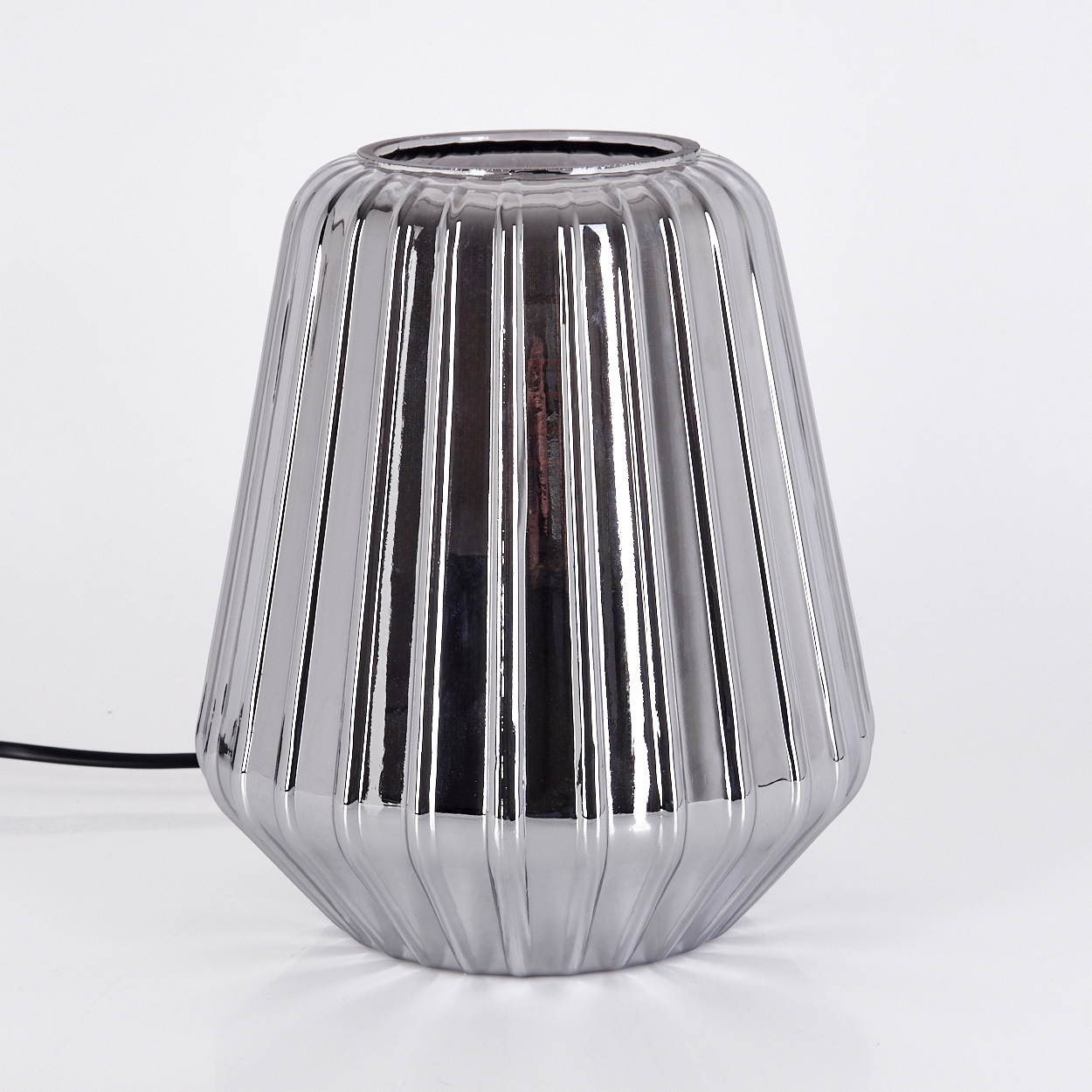Eine silberne, gerippte Vase steht auf weißem Untergrund.