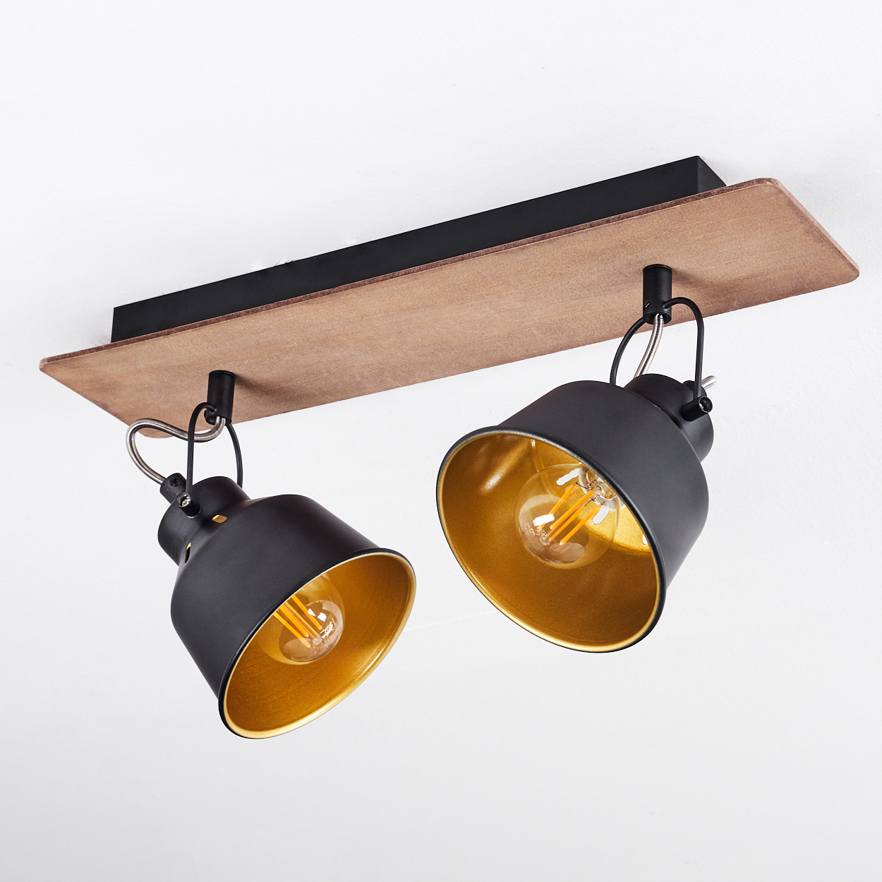 Zwei schwarze Deckenstrahler mit goldenen Innenseiten auf Holzbasis.