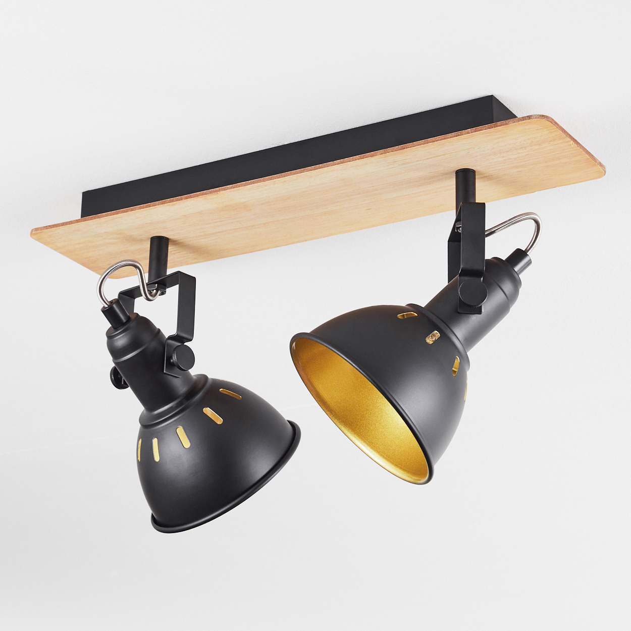 Zwei schwarze Strahler mit goldenen Innenseiten auf Holzmontage.
