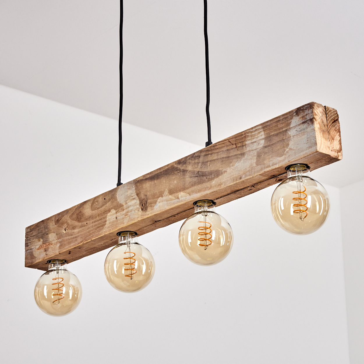 Ein rustikaler Holzbalken mit vier Edison-Glühbirnen an schwarzen Kabeln.