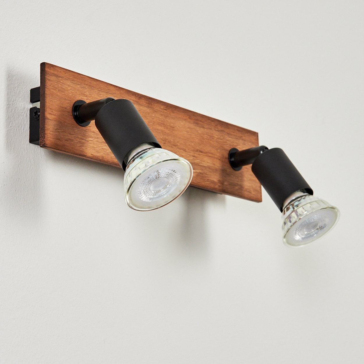 Doppeltes Wandlicht mit Holzbasis und schwarzen verstellbaren Lampen.