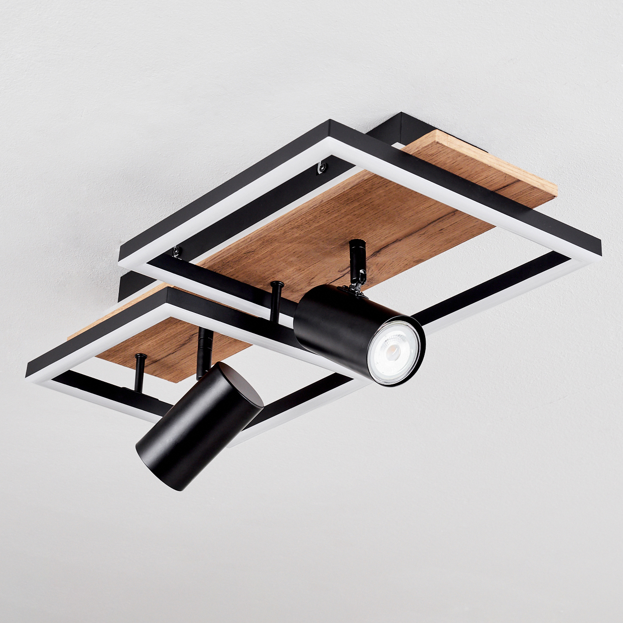 Moderne Deckenleuchte mit Holzdetails und zwei schwenkbaren schwarzen Spots auf weißem Hintergrund.