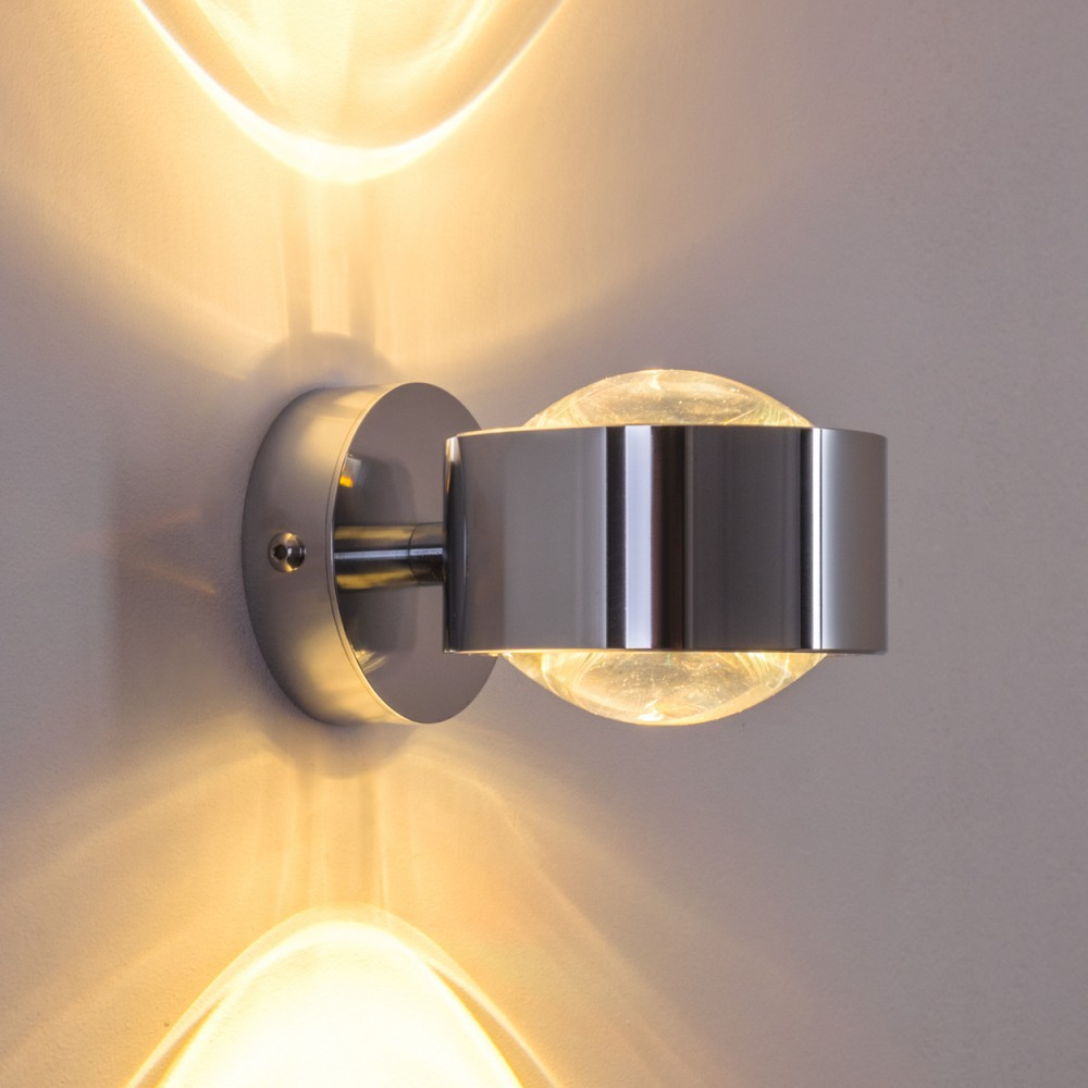 Moderne silberne Wandleuchte mit klarer Glaskugel und metallischen Akzenten.