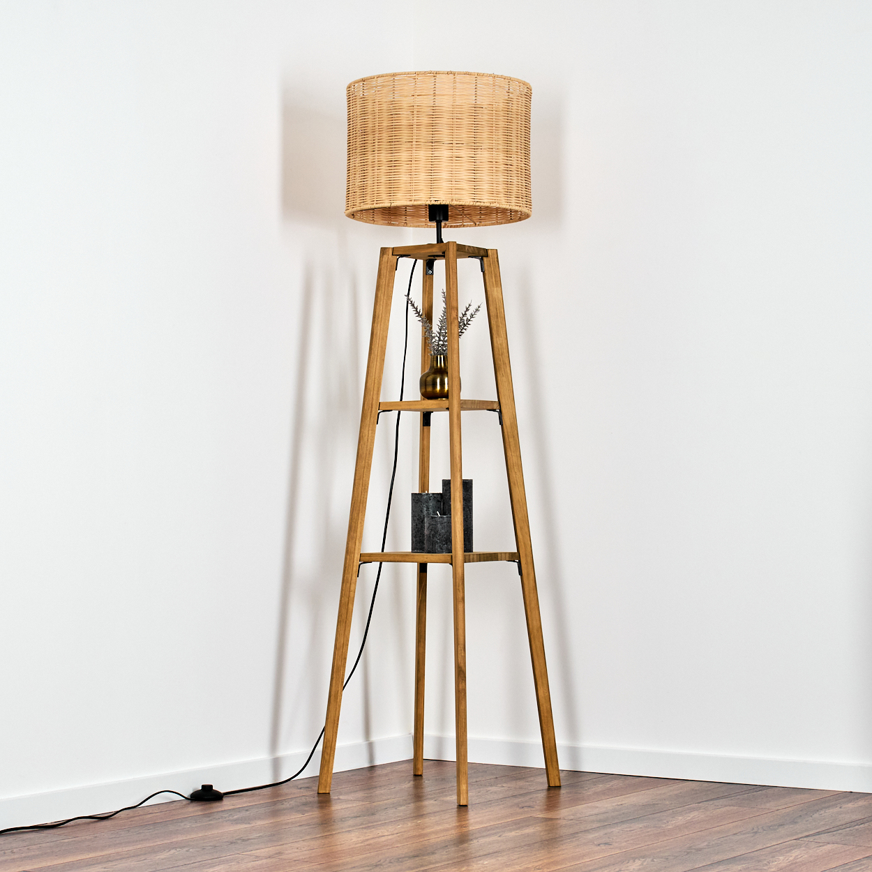 Ein Stehlampe aus Holz mit einem geflochtenen Schirm steht auf einem Holzboden.