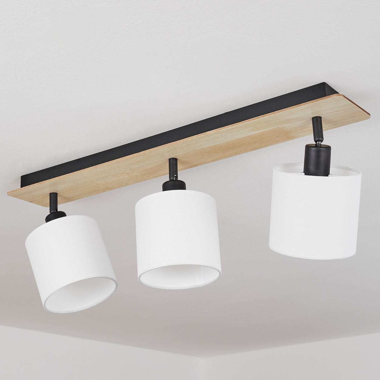 Deckenleuchte mit Holzsockel und drei weißen Lampenschirmen.