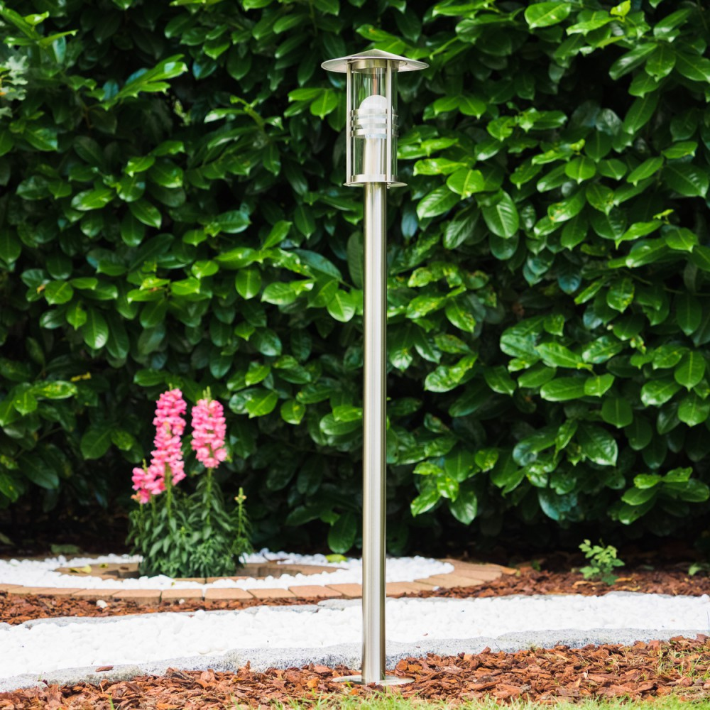 Ein moderner Gartenweg mit Lampe, Blumen und Hecke.