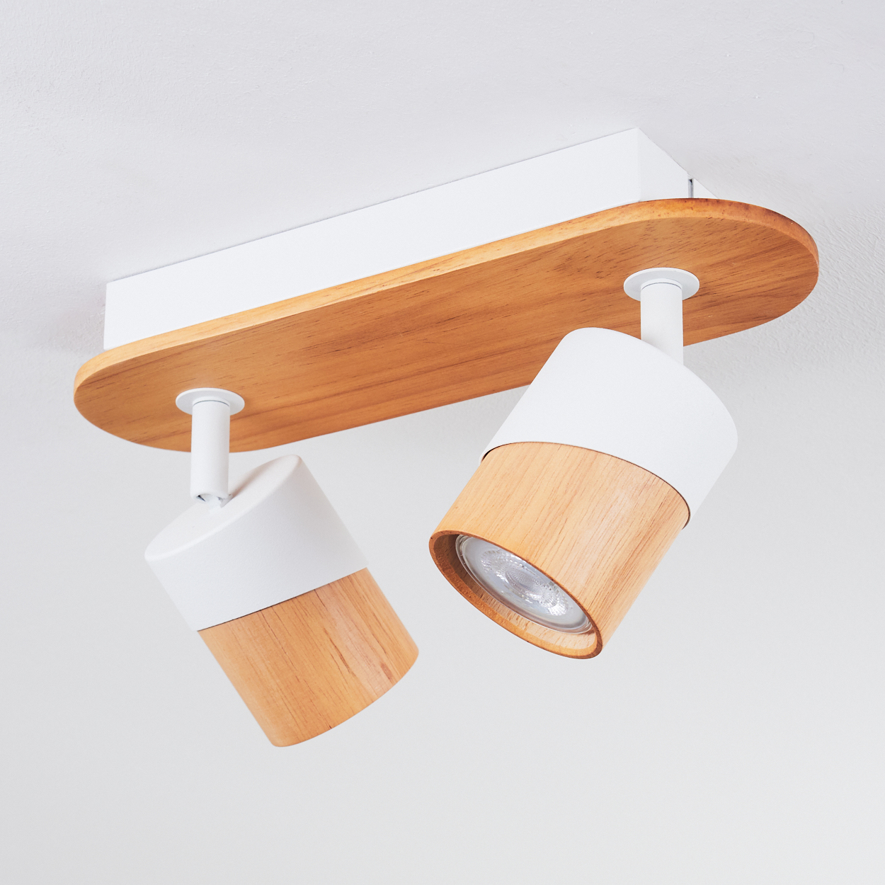 Deckenleuchte mit Holz- und Weißakzenten und zwei verstellbaren Spots.