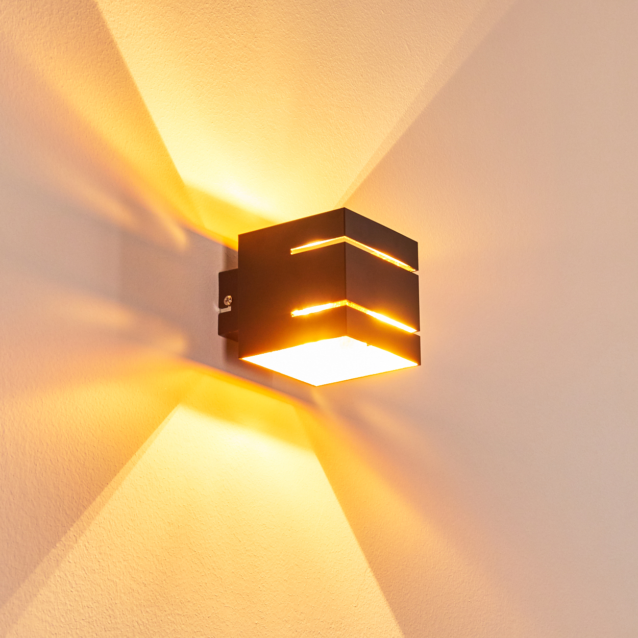 Schwarzer Würfel-Wandleuchter mit warmem Licht, das nach oben und unten abstrahlt.