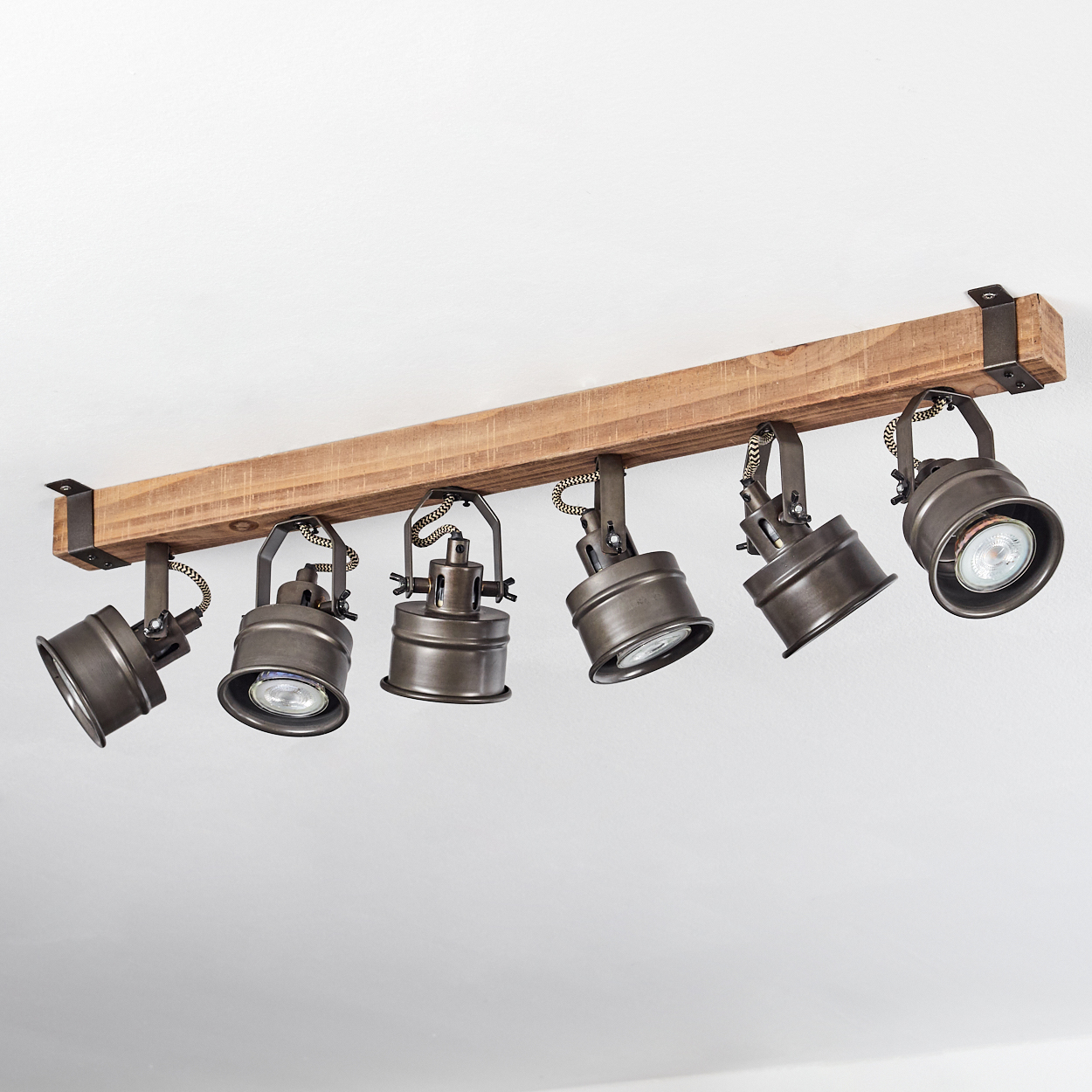 Ein Holzbalken mit sechs angebrachten antiken Bronzescheinwerfern.