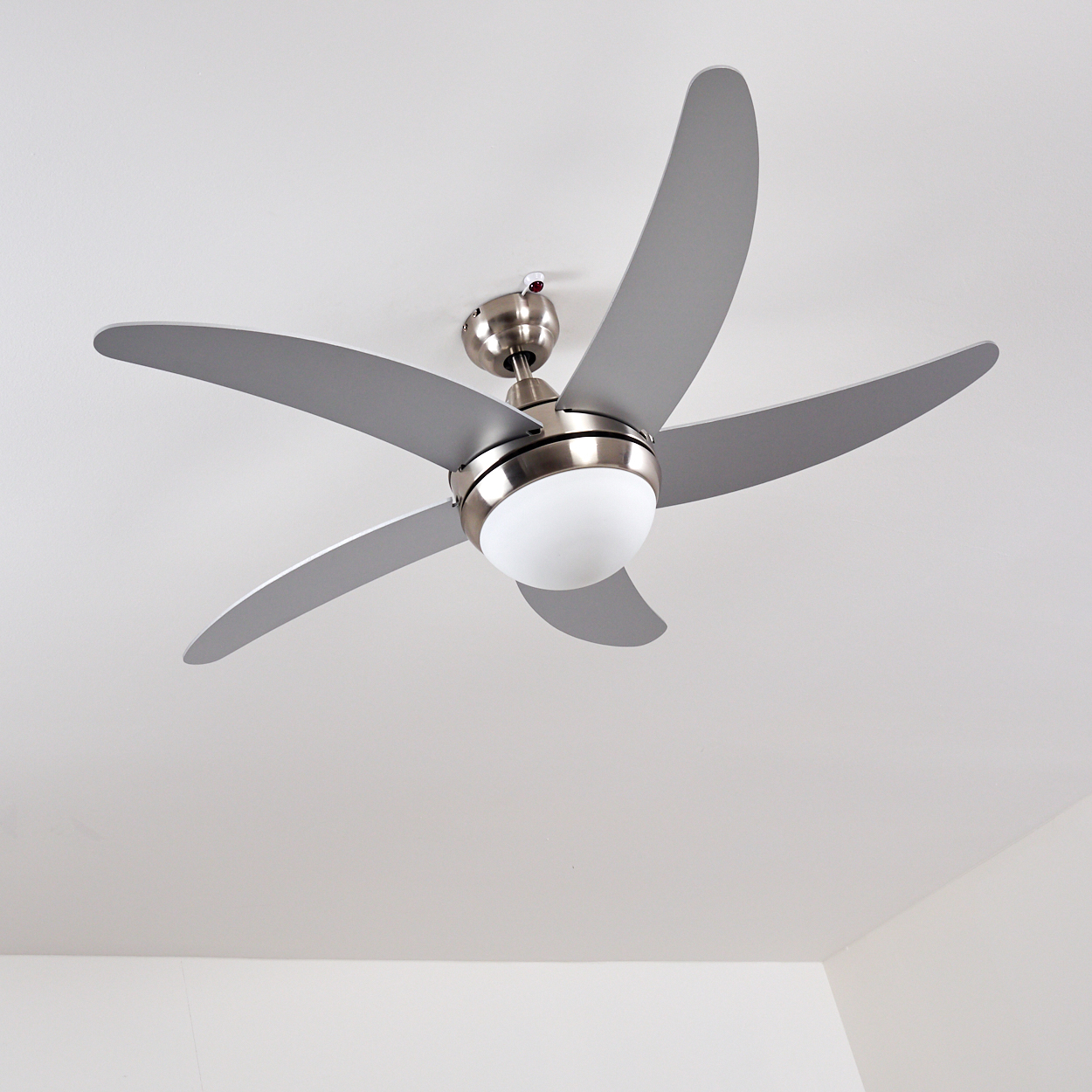 Ein moderner silberner Deckenventilator mit fünf Flügeln und zentraler Leuchte.
