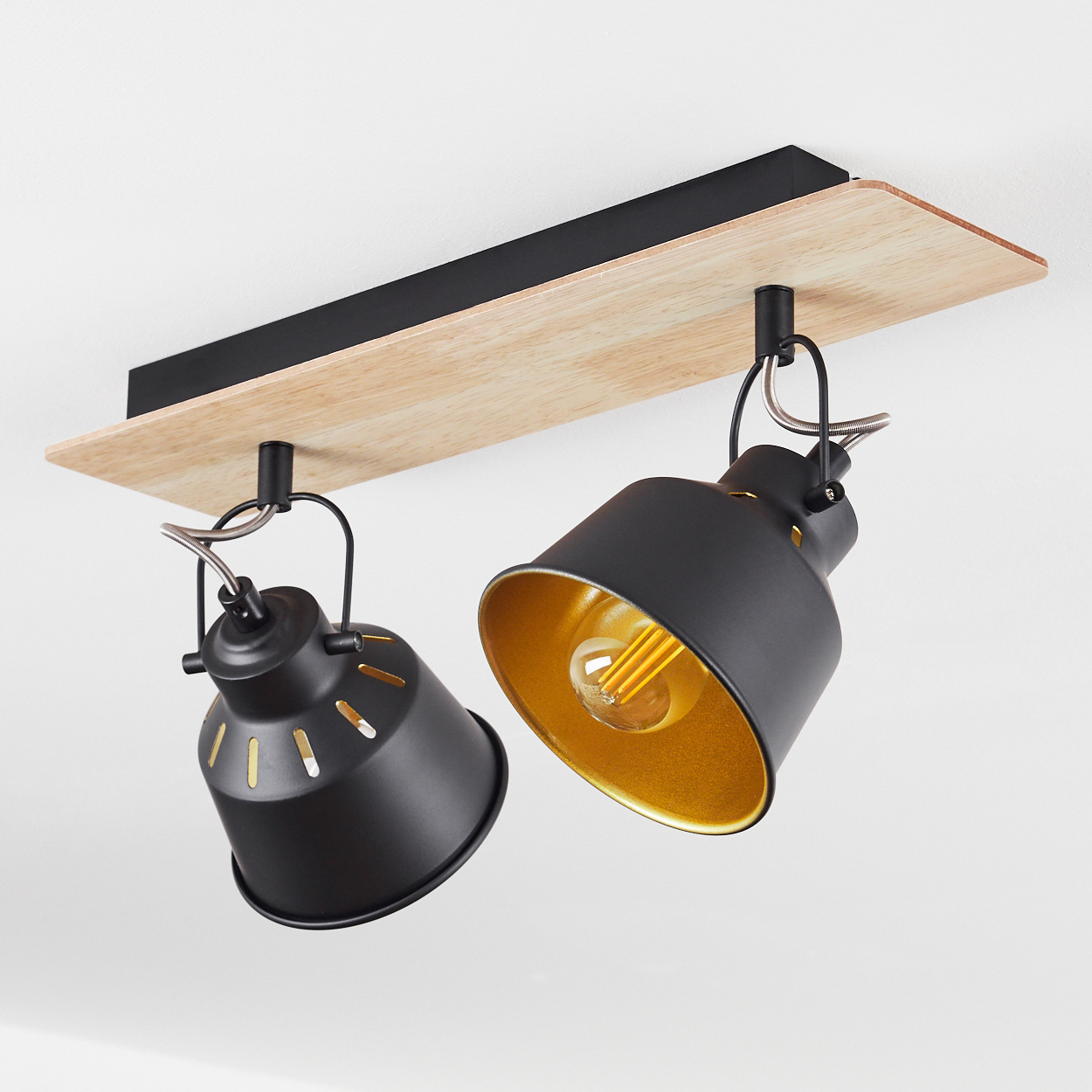 Zwei schwarze Lampen mit goldener Innenseite hängen an Holzbalken.