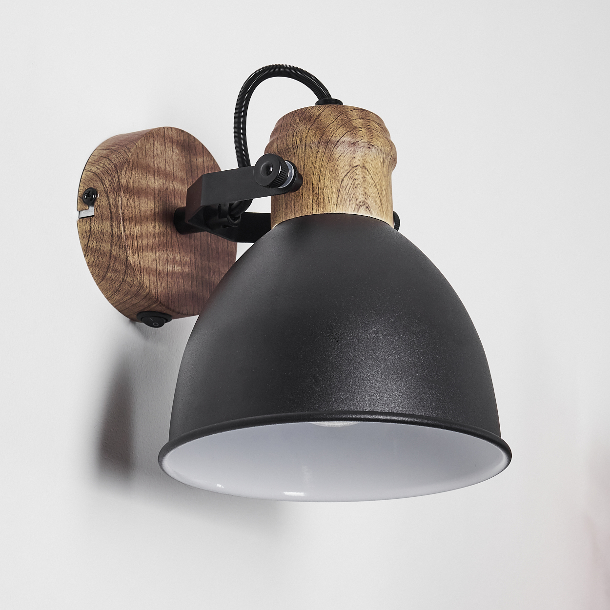 Eine Wandleuchte mit Holzbasis, schwarzem Lampenschirm und weißem Inneren.