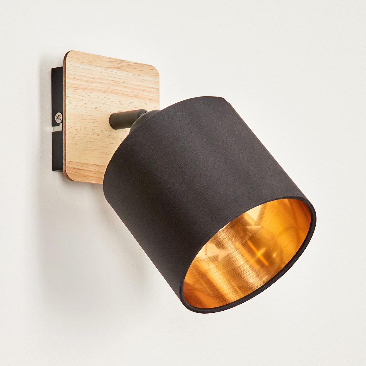 Ein moderner Wandspot mit Holzsockel, schwarzem Schirm und goldener Innenseite.