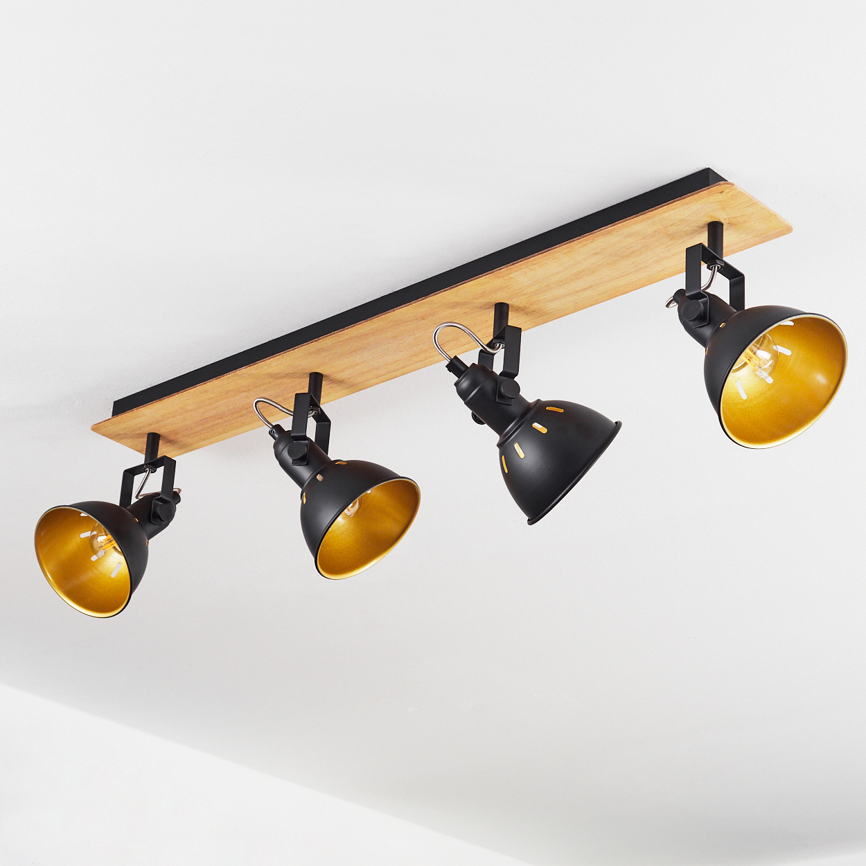 Vier schwarze Spots mit goldenem Innenleben auf Holzplanke montiert.