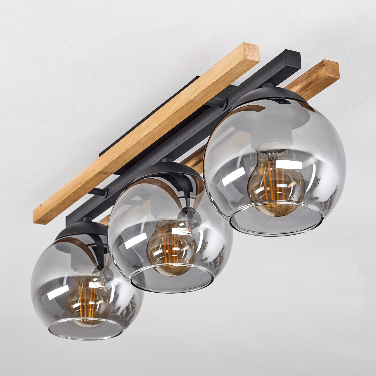 Deckenleuchte mit drei Rauchglasglocken und Holzdetails.