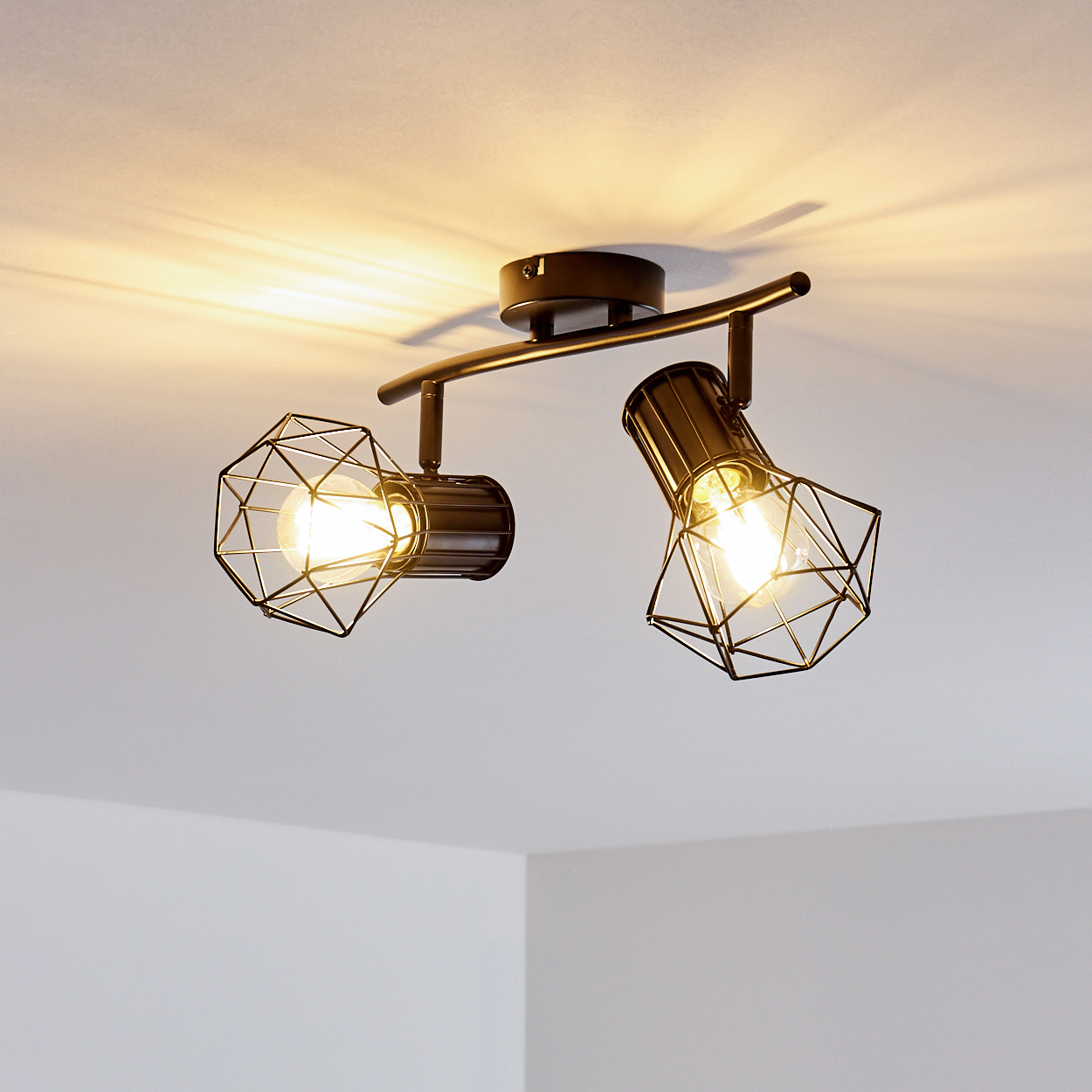 Schwarzer Deckenstrahler mit zwei geometrischen Lampenschirmen und sichtbaren Glühbirnen.