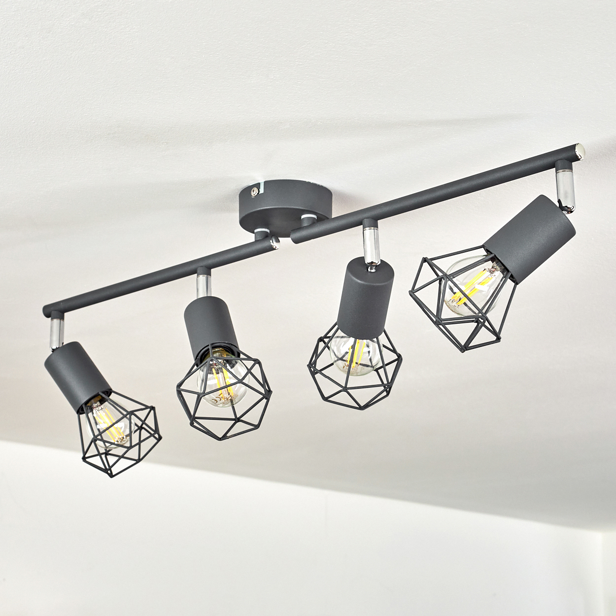 Schwarzer Deckenstrahler mit vier Lampen und geometrischen Käfigschirmen.