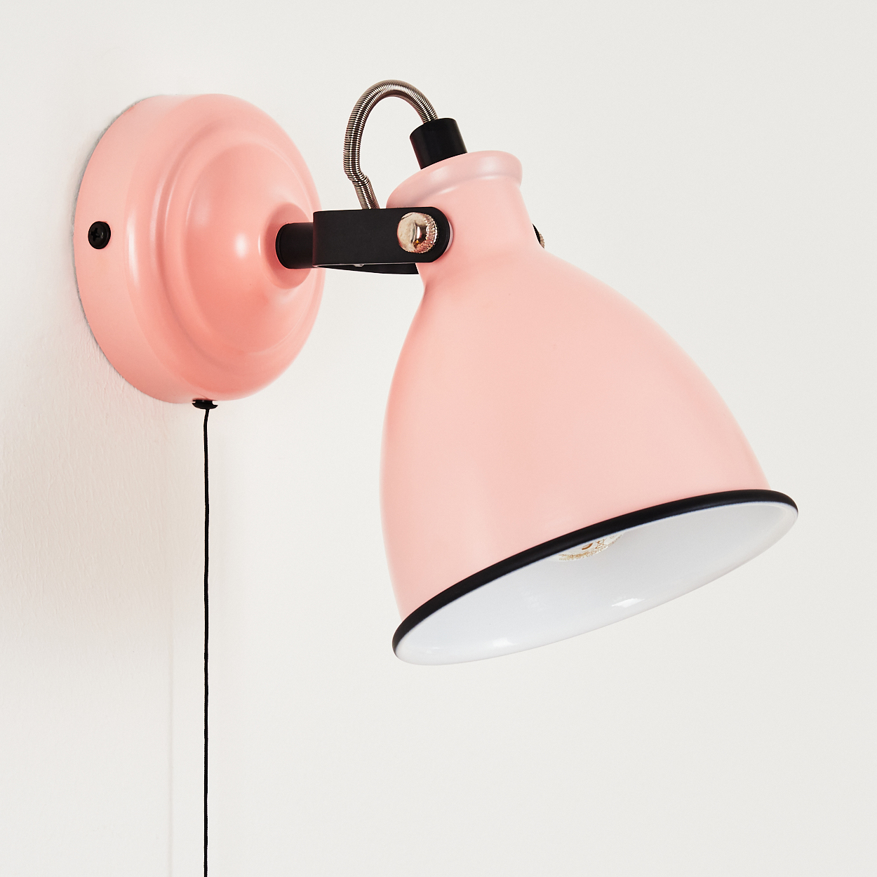 Eine rosafarbene Wandlampe mit schwarzem Schwenkarm und Schnurschalter.