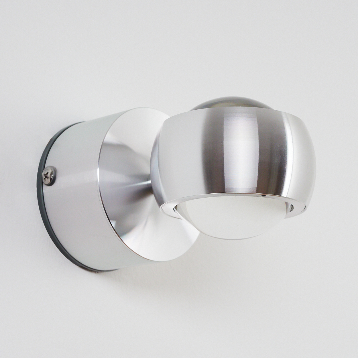 Ein moderner silberner Wandspot mit verstellbarem Lampenkopf und Milchglas.