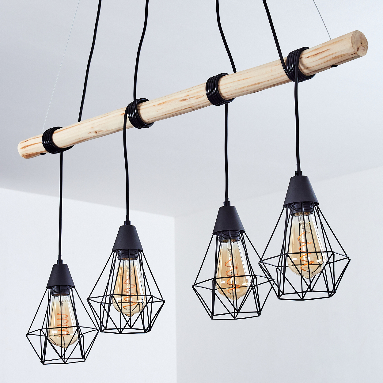 Ein Holzbalken mit vier schwarzen Pendelleuchten mit Edison-Glühbirnen.