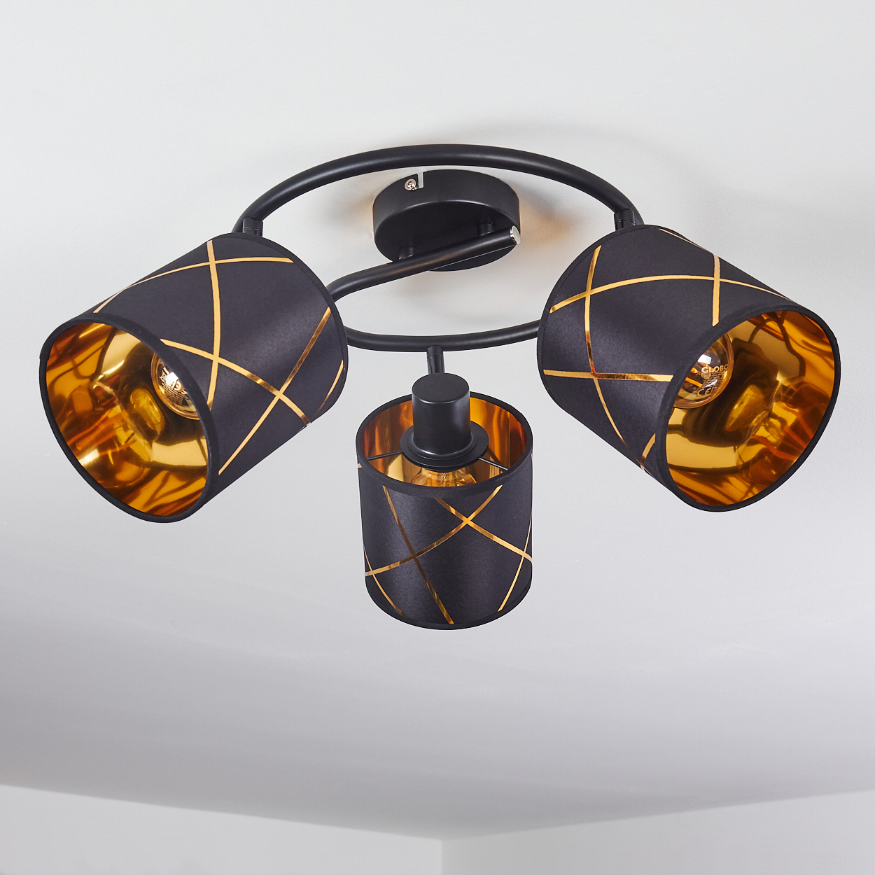 Eine schwarze Deckenleuchte mit drei Lampenschirmen, verziert mit goldenen Linien.