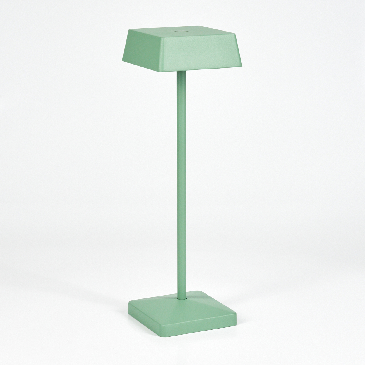 Ein grüne Tischlampe mit rechteckigem Lampenschirm und Sockel steht auf weißem Grund.