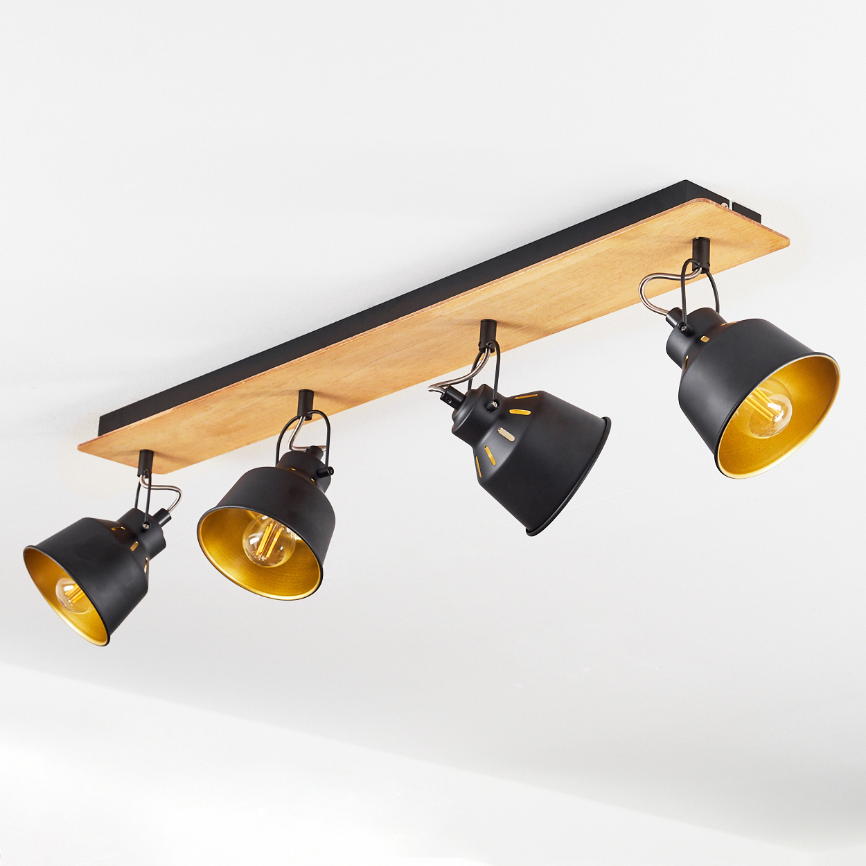 Schwarze Deckenleuchte mit Holzsockel und vier verstellbaren Spots mit goldenen Innenseiten.