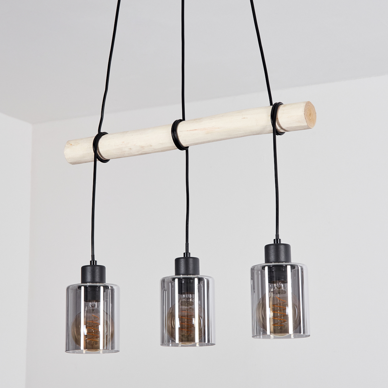 Pendelleuchte mit Holzstange und drei Glaslampenschirmen.
