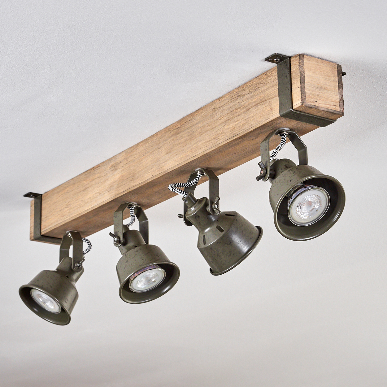 Ein Holzbalken mit vier grünen Spots, die an der Decke montiert sind.