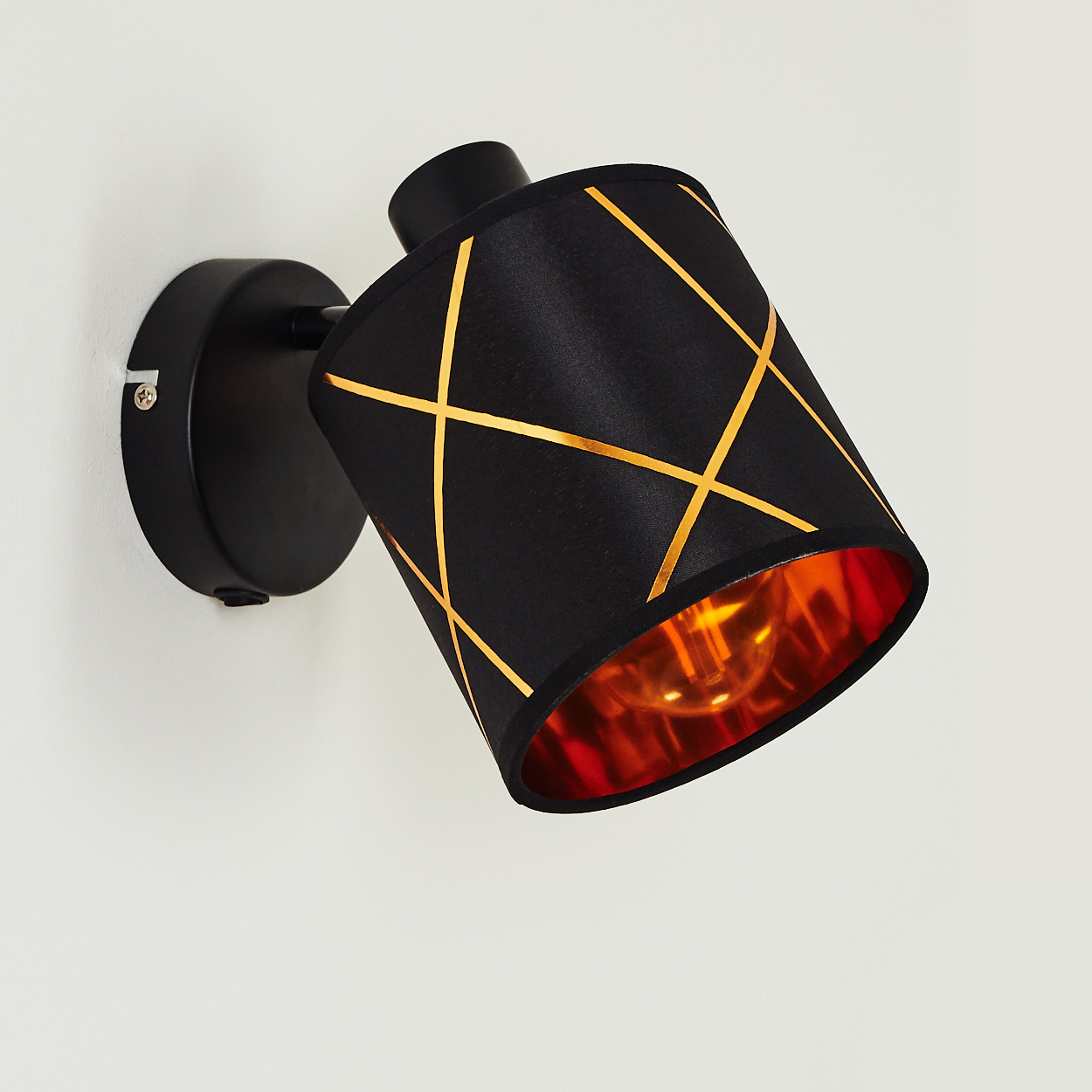 Schwarzer Wandspot mit goldenem Gittermuster und kupferfarbenem Innenleben.