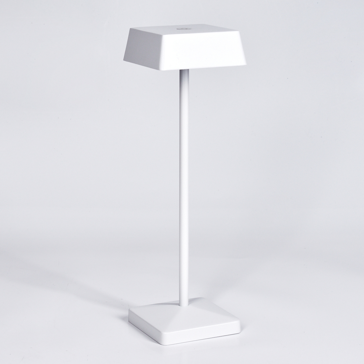 Eine weiße Tischlampe mit einem rechteckigen Lampenschirm und einem schlanken Ständer.