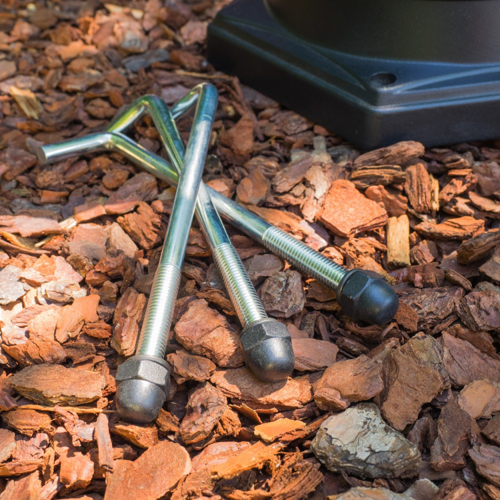 Drei Metallstangen mit schwarzen Endkappen liegen auf Rindenmulch.