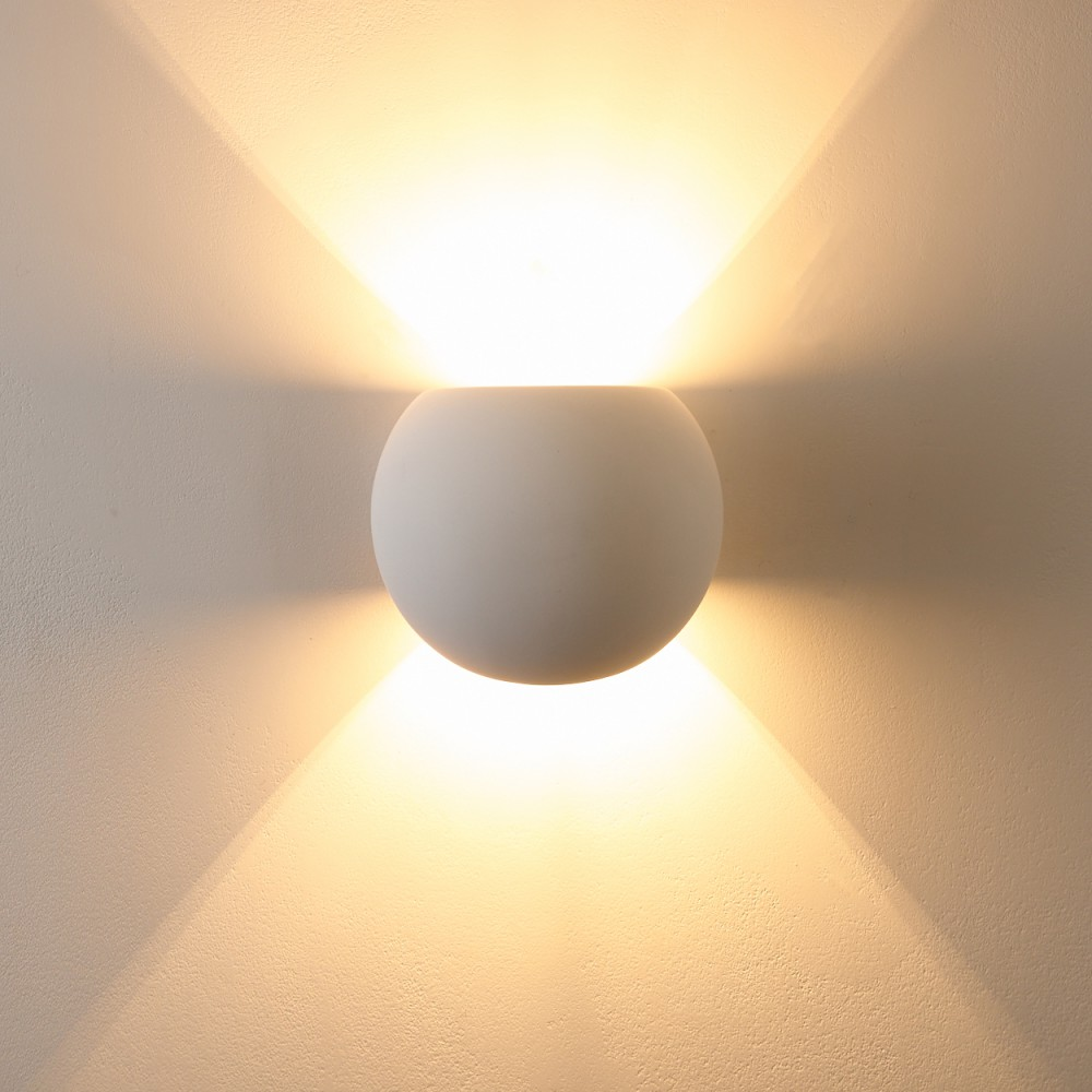 Eine kugelförmige weiße Wandleuchte strahlt helles Licht nach oben und unten ab.