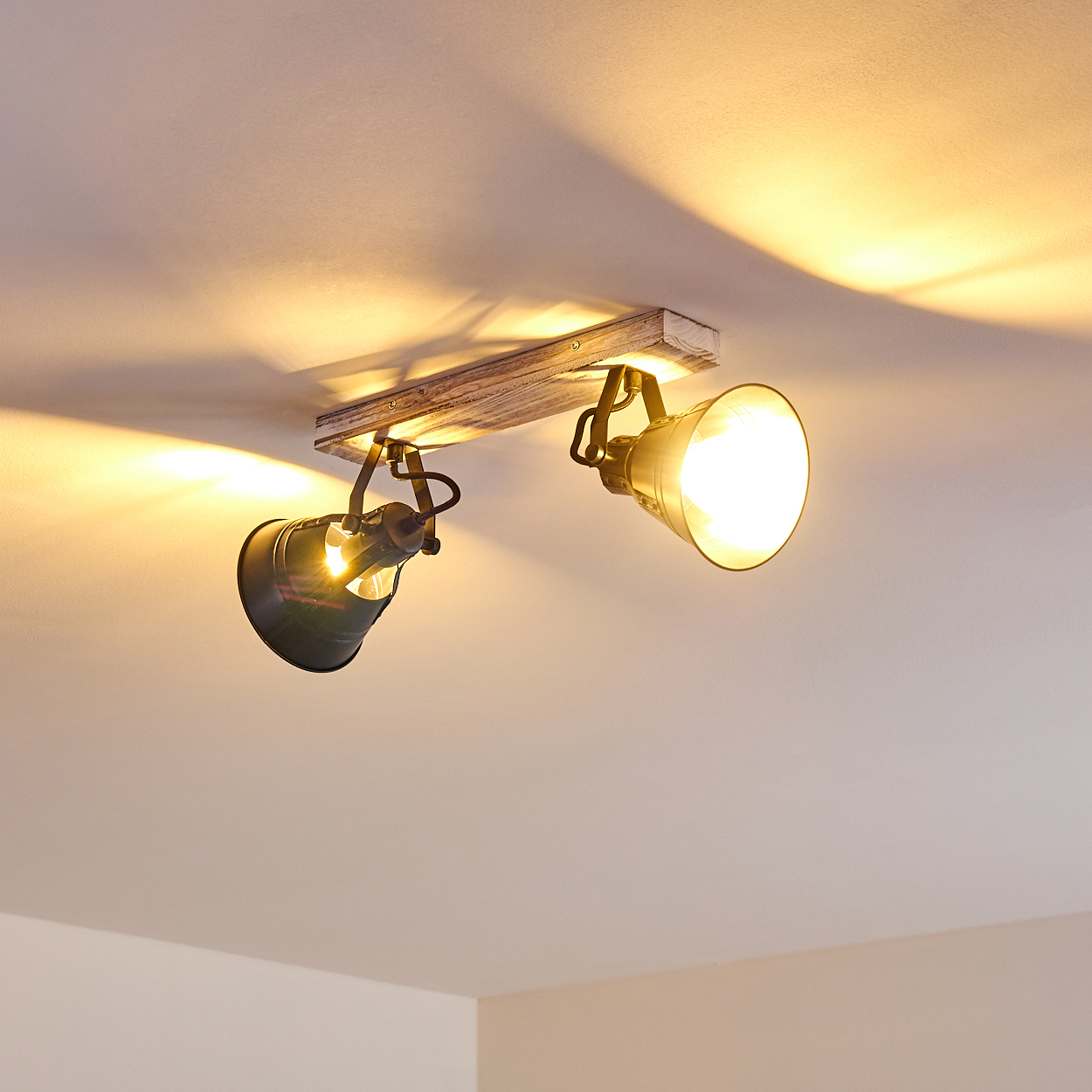 Zwei gerichtete Lampen an Holzbalken an der Decke leuchten gelb.