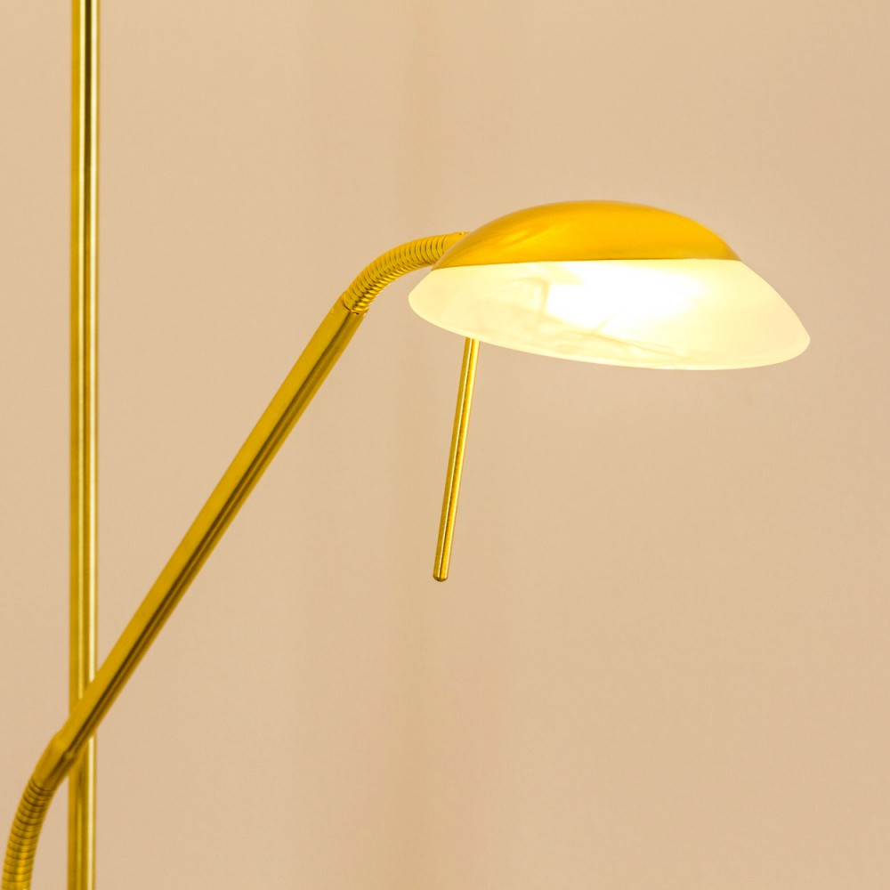 Eine goldene Stehlampe mit einem gelben Schirm und einer Milchglasscheibe.