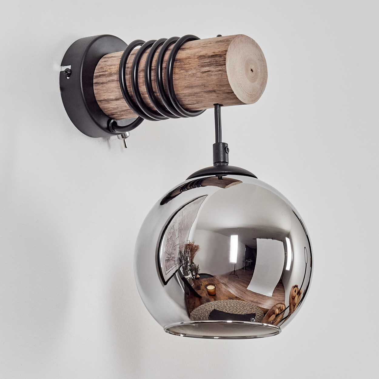 Ein Wandleuchter mit Holz, Metall und einer reflektierenden Kugel.
