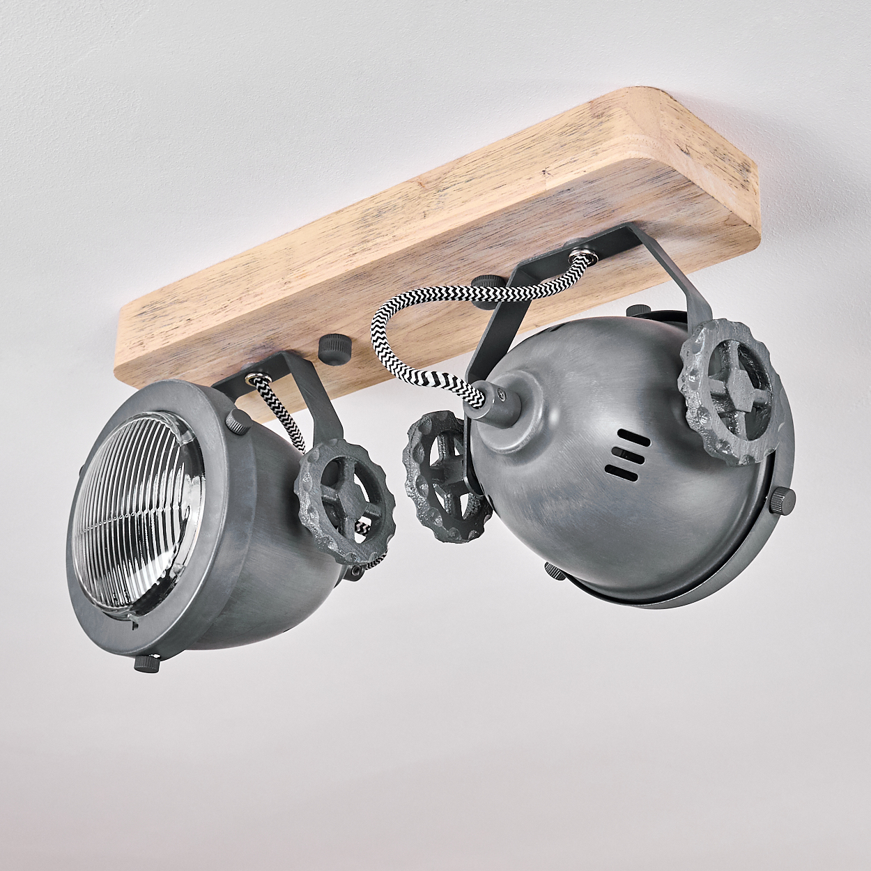 Eine Deckenleuchte mit Holzsockel und zwei grauen Metallscheinwerfern mit Zahnrad-Details.